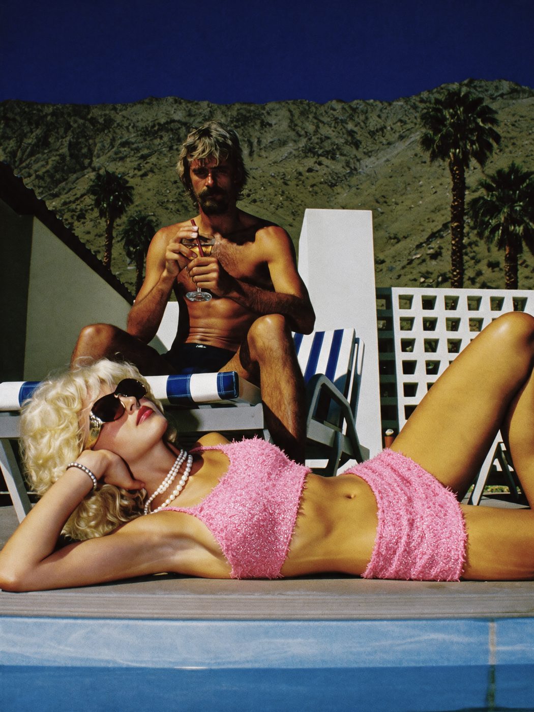 AI image: a couple by a pool with mountains and palm trees